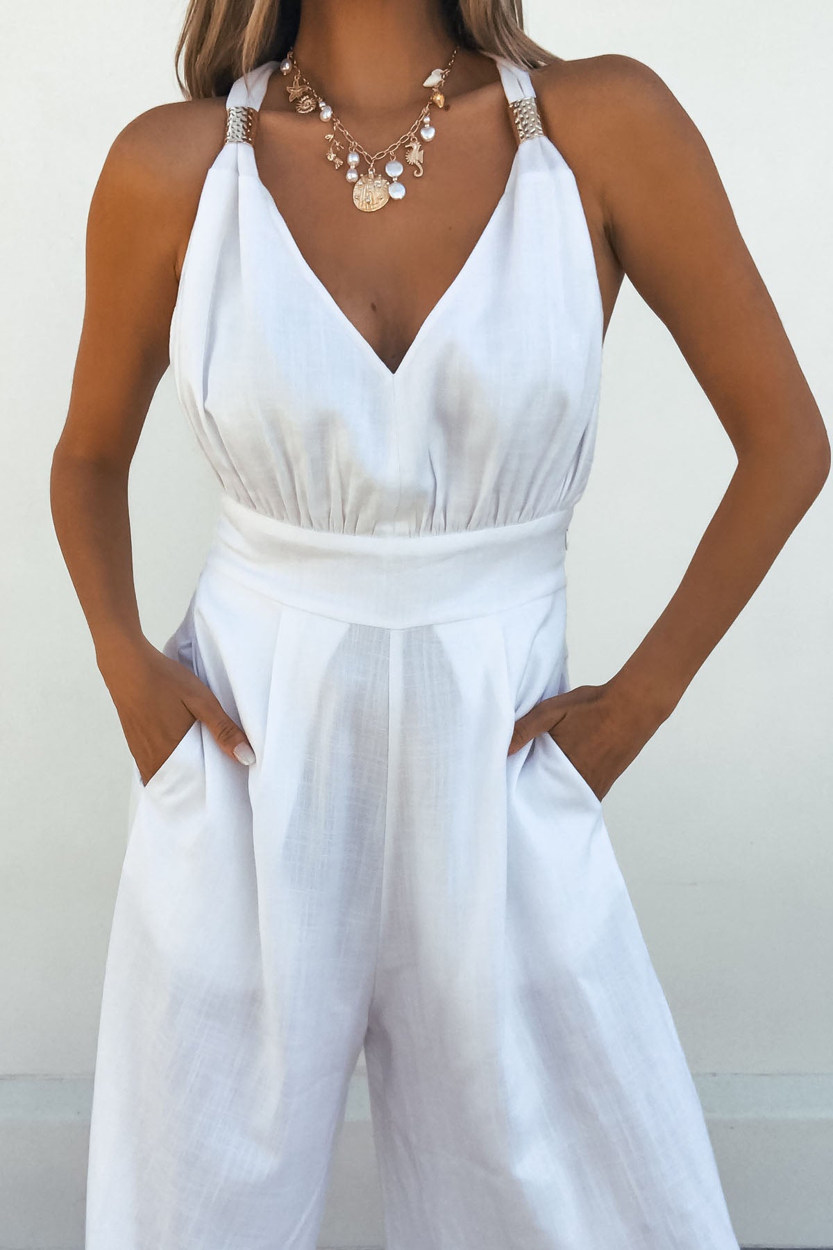 Woman in the Vintage Havana White Gold Detail Linen Jumpsuit poses with hands in pockets against a plain background.