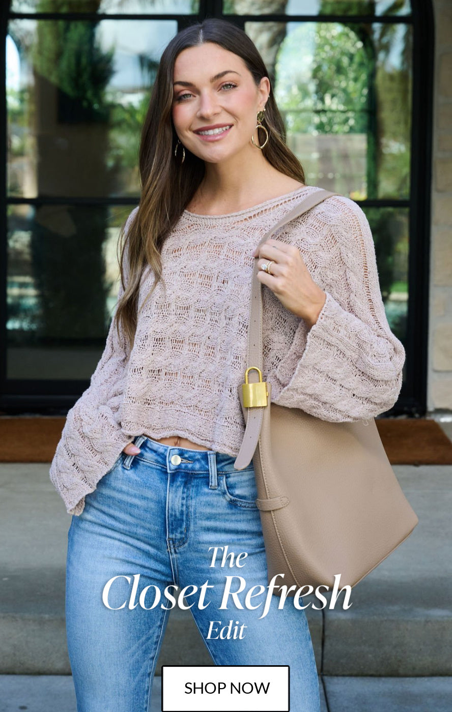 Woman wearing a beige sweater and blue jeans, holding a beige handbag with 'The Closet Refresh Edit' text.