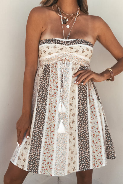 Woman in a Multi-Color Print Strapless Tunic, styled with layered necklaces and a bracelet—perfect for your summer wardrobe.