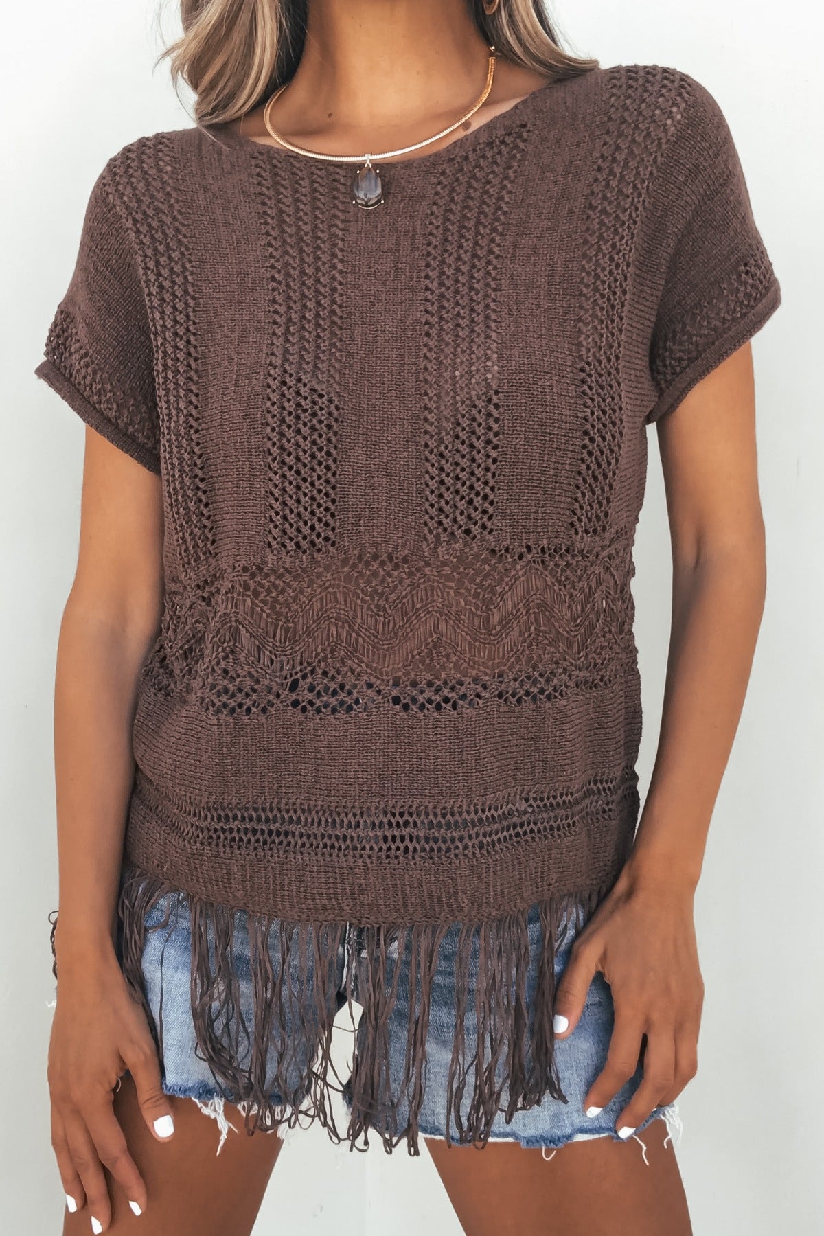 Model in Boho Fringe Sweater - Brown paired with light blue denim shorts, posing against a white background.