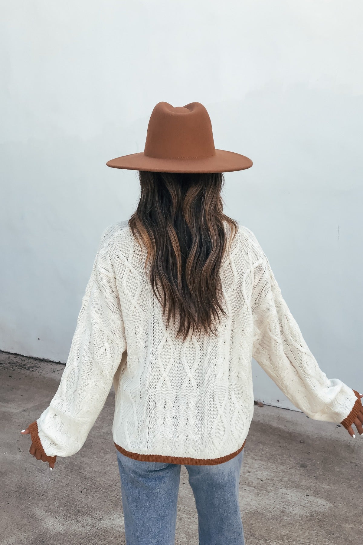 Person wearing the Cream Contrast Trim Cardigan, brown hat, and jeans stands with back to camera against a plain wall.
