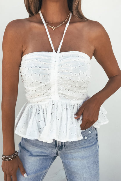 Woman wearing the Adeline Eyelet Smocked Halter Top - White with light blue jeans and layered necklaces for summer style.