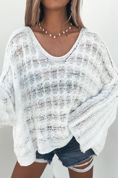 Woman in the Calista Open Knit Top - Ivory, paired with denim shorts and shell necklace for an effortless coastal look.