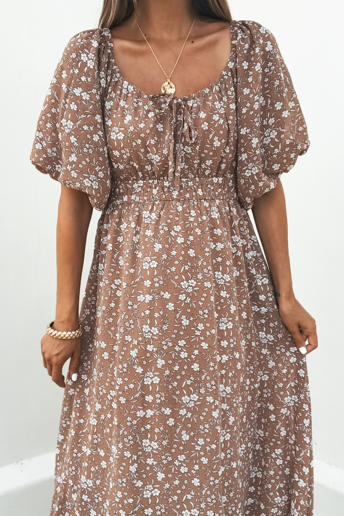 Woman in Prairie Bloom Maxi Dress - Tan with necklace and bracelet stands against a white background.
