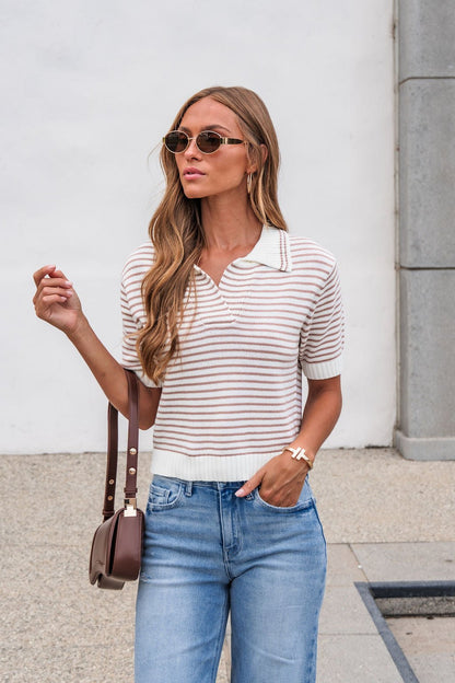 Woman in sunglasses wears the Adair Striped Sweater - Dark Taupe, blue jeans, and a brown purse near a white wall.