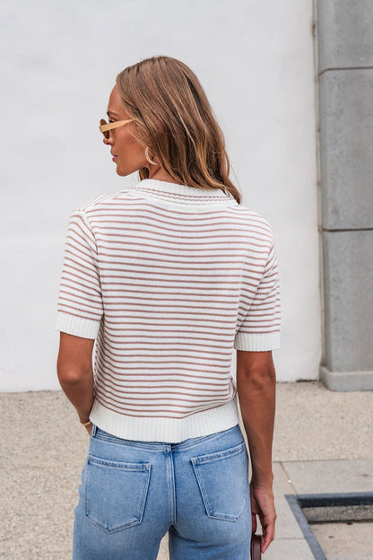 Woman with wavy hair wears the Adair Striped Sweater - Dark Taupe, sunglasses, and blue jeans outdoors, facing away from the camera.