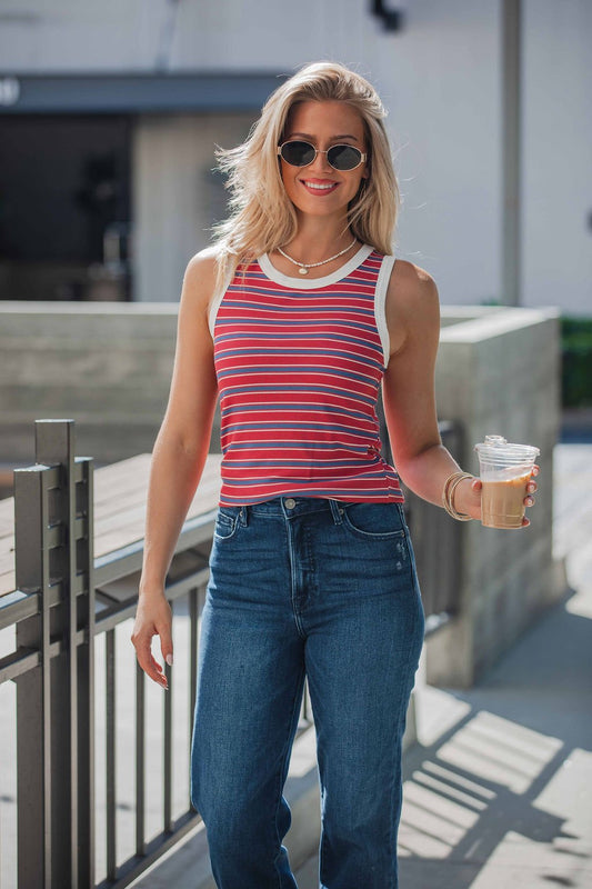 Woman in sunglasses wears the All-Day Stripe Tank Top - Red and holds an iced coffee while walking outdoors on a sunny day.
