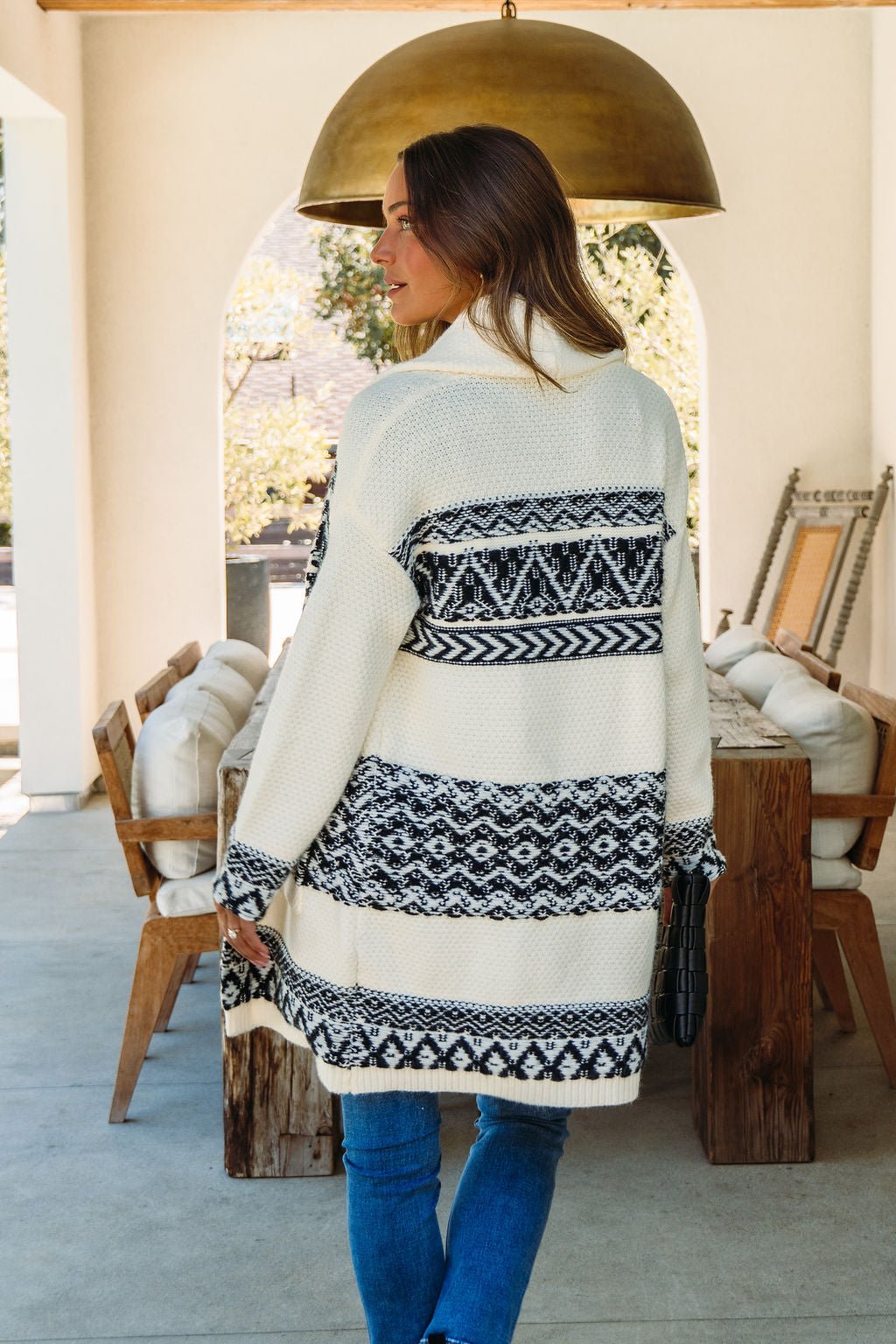 A woman stands outdoors in the Alpine Retreat Ivory and Black Shawl Cardigan, ideal for fall and winter wear.