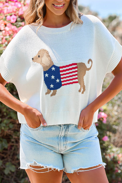 Woman in denim shorts wears the Patriotic Pup Knit Sweater - Cream, featuring a dog and flag, standing outside by flowers.