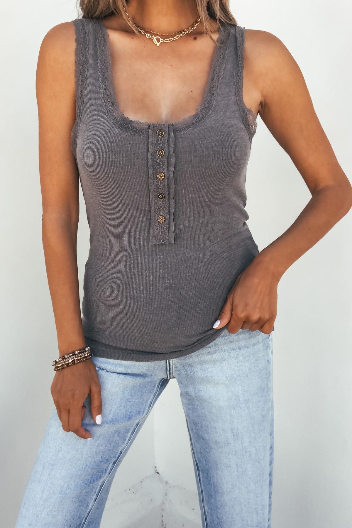 Woman wears the Ashlyn Lace Trim Button Tank – Grey with light blue jeans, standing against a plain white background.