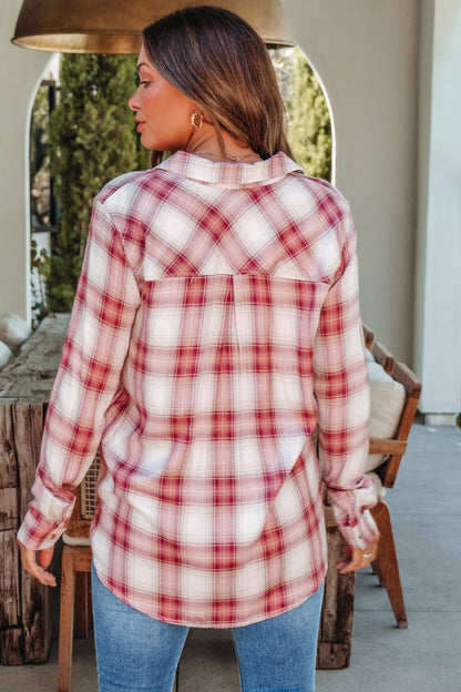 A woman in an Autumn Spice Wine Plaid Shirt and blue jeans stands outdoors with her back to the camera.