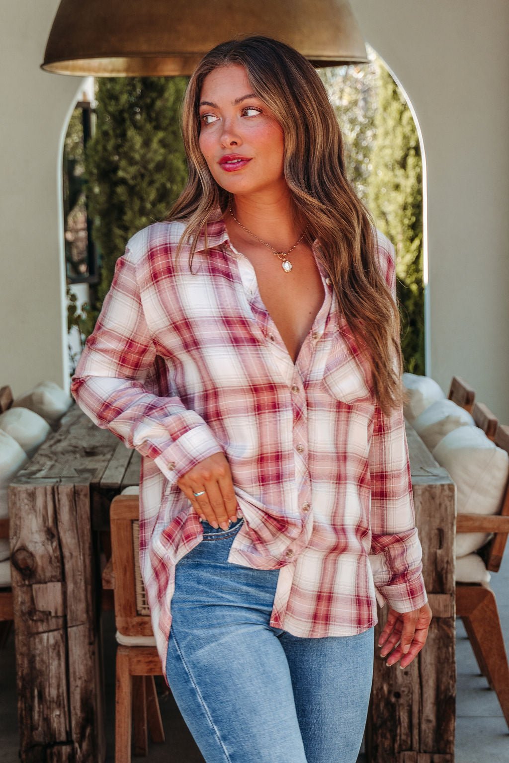 Wearing the Autumn Spice Wine Plaid Shirt and blue jeans, she stands indoors—an ideal rustic fall wardrobe look.
