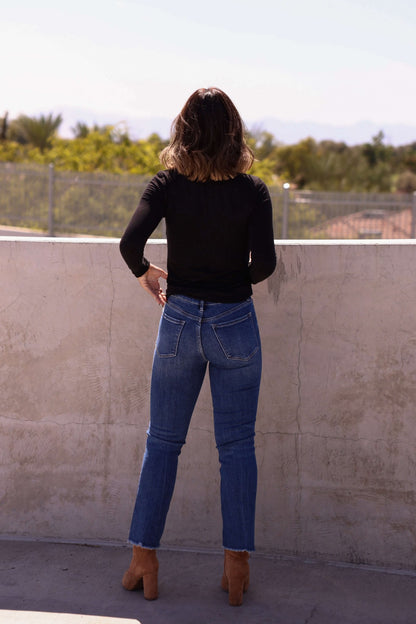 A woman stands on a wall in Bayeas Dark Wash Mid Rise Bootcut Jeans.