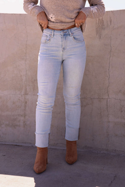 Person wearing Bayeas Light Blue Straight Leg Cuffed Jeans—FINAL SALE—with brown boots and a beige sweater by a concrete wall.