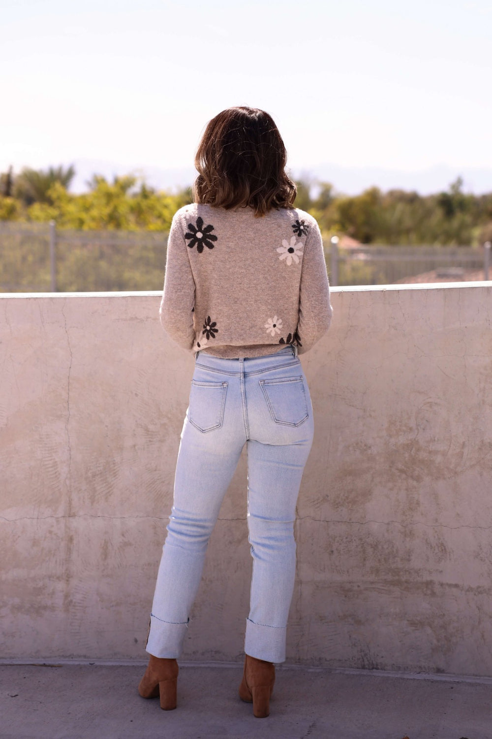A woman with wavy hair wears Bayeas Light Blue Straight Leg Cuffed Jeans—Final Sale—while standing outdoors, back to camera.