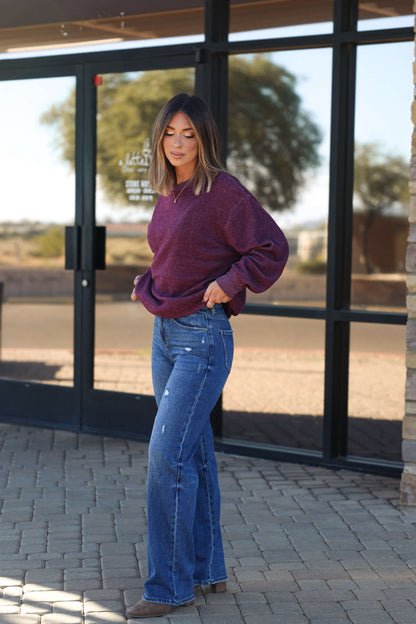 A woman in Bayeas Medium Wash Relaxed Straight Leg Jeans stands outside on a brick walkway by glass doors and a stone wall.