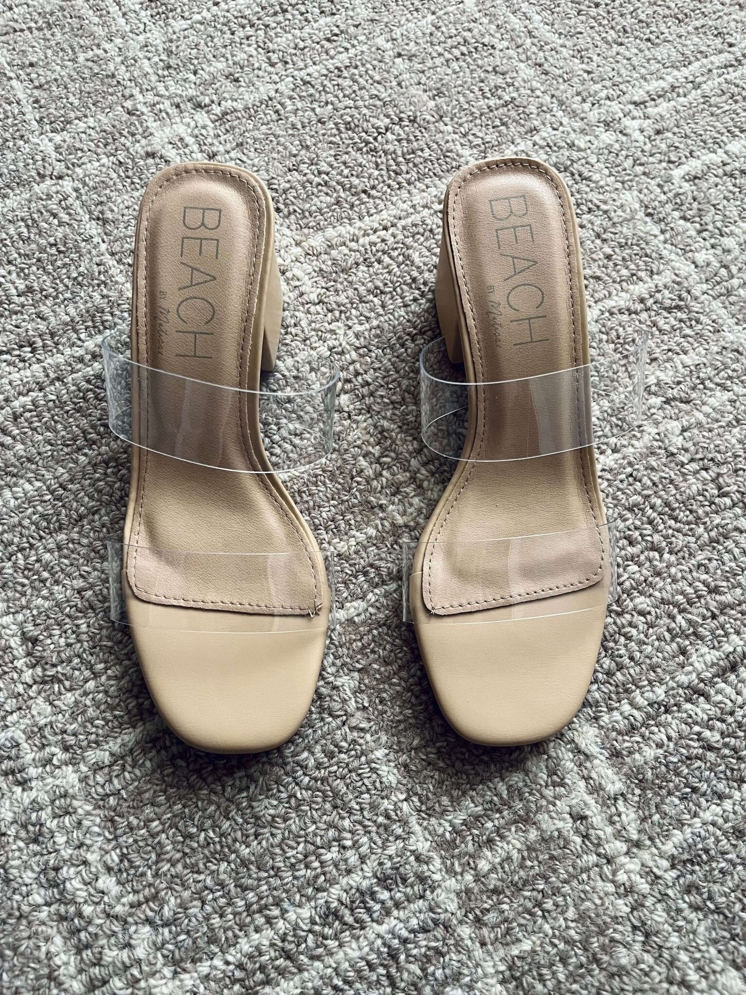 Beach by Matisse Aura Nude Strappy Heels with clear straps, shown on a textured carpet.