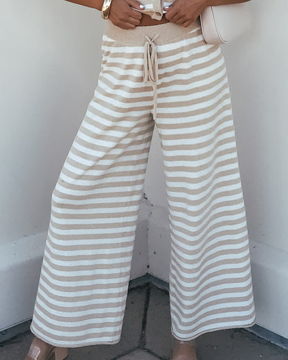 Woman wearing Beige and Ivory Striped Lounge Pants | Pre Order, holding a light purse, lower body visible.
