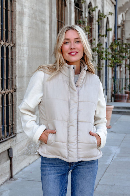 A woman in a Beige Button Up Puffer Vest and jeans smiles outdoors—ideal for chic autumn outfits and casual fall layering.