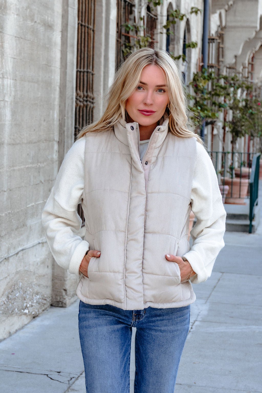 A woman in a Beige Button Up Puffer Vest and blue jeans showcases chic, effortless fall layering on a city sidewalk.