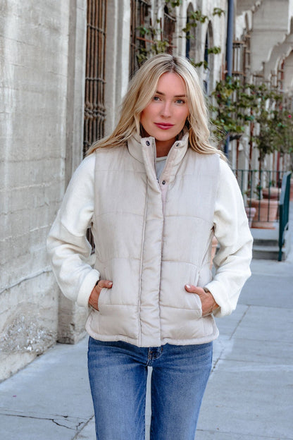 A woman in a Beige Button Up Puffer Vest and blue jeans showcases chic, effortless fall layering on a city sidewalk.