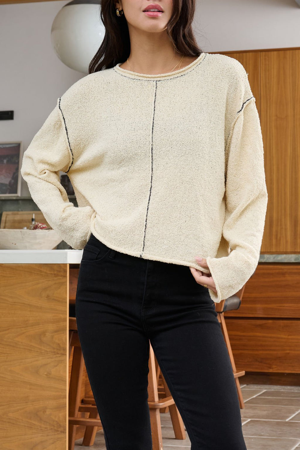 Woman wearing the Beige Contrast Stitch Detail Sweater - FINAL SALE and black pants, standing in a modern kitchen.