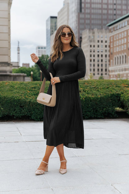 A woman wears the Black Contrast Pleated Midi Dress, featuring elegant ribbed details.