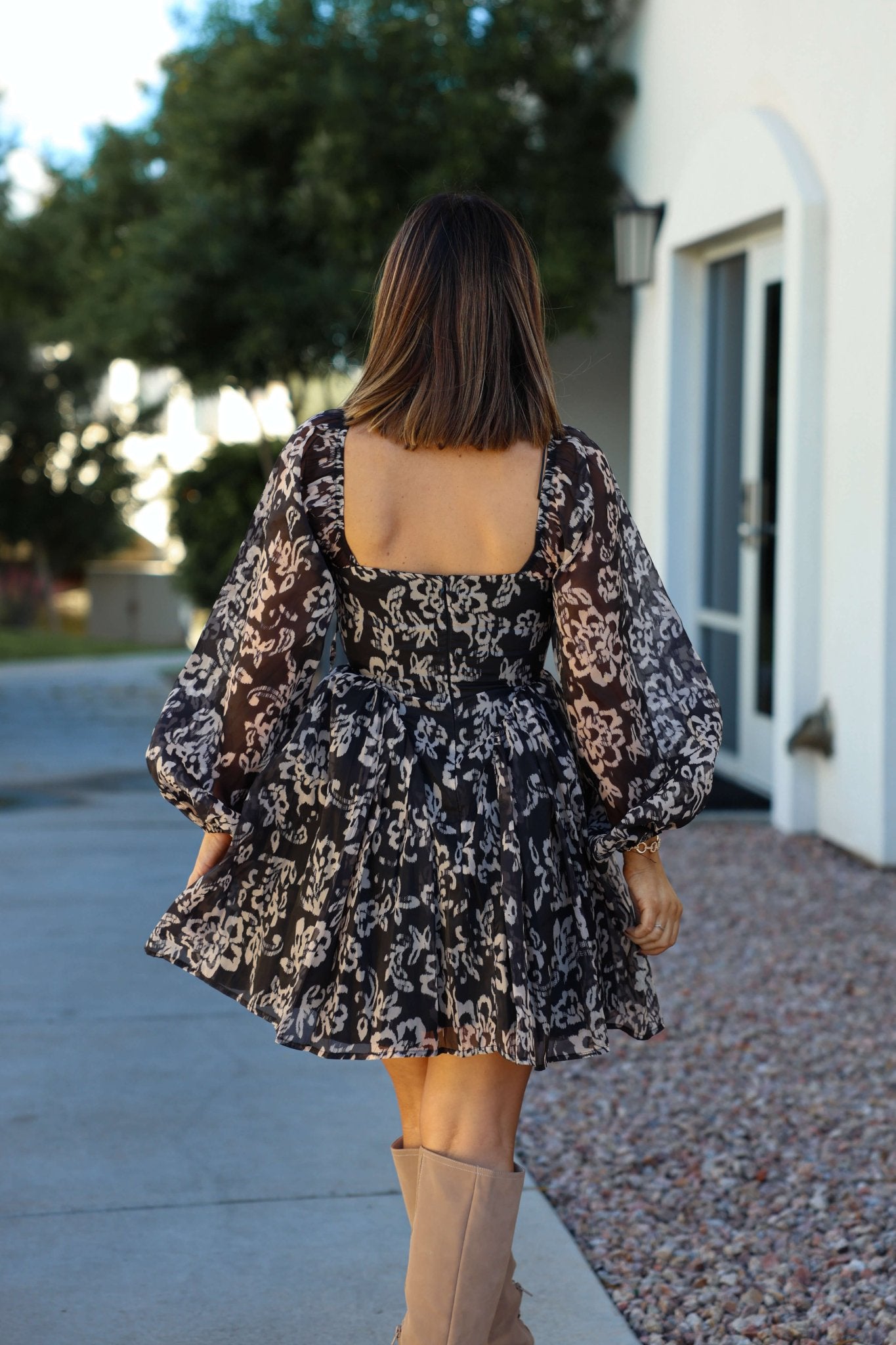 A woman with shoulder-length hair wears a Black Floral Chiffon Corset Mini Dress outdoors.