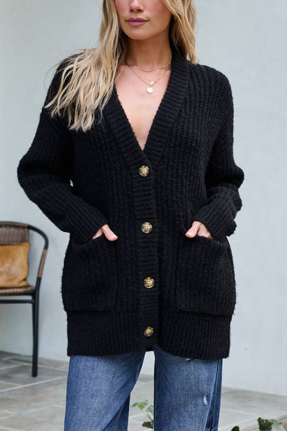 Woman wearing the Basic Black Knit Button Down Cardigan with blue jeans, standing in front of a chair outdoors.