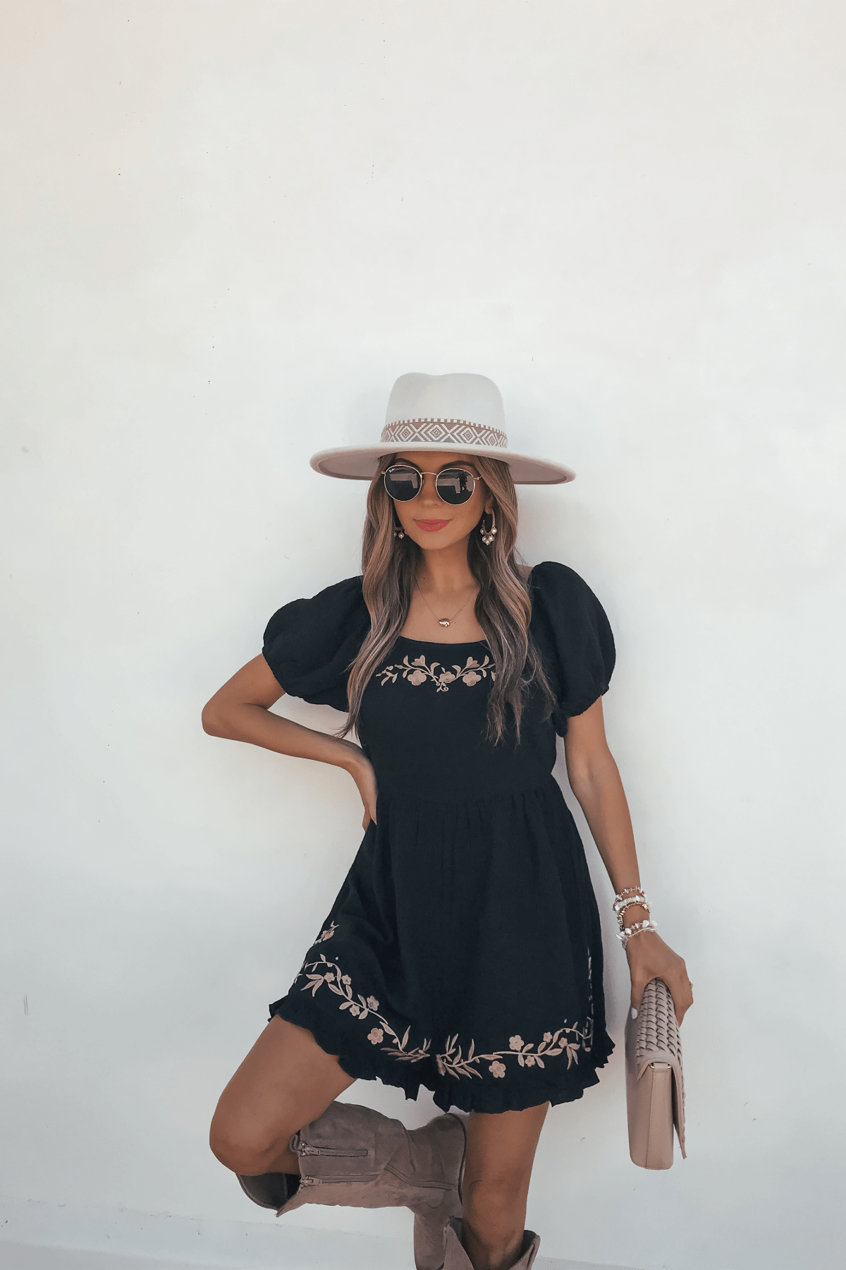 Woman in a Black Puff Sleeve Embroidered Romper and a wide-brim hat, posing against a white background.