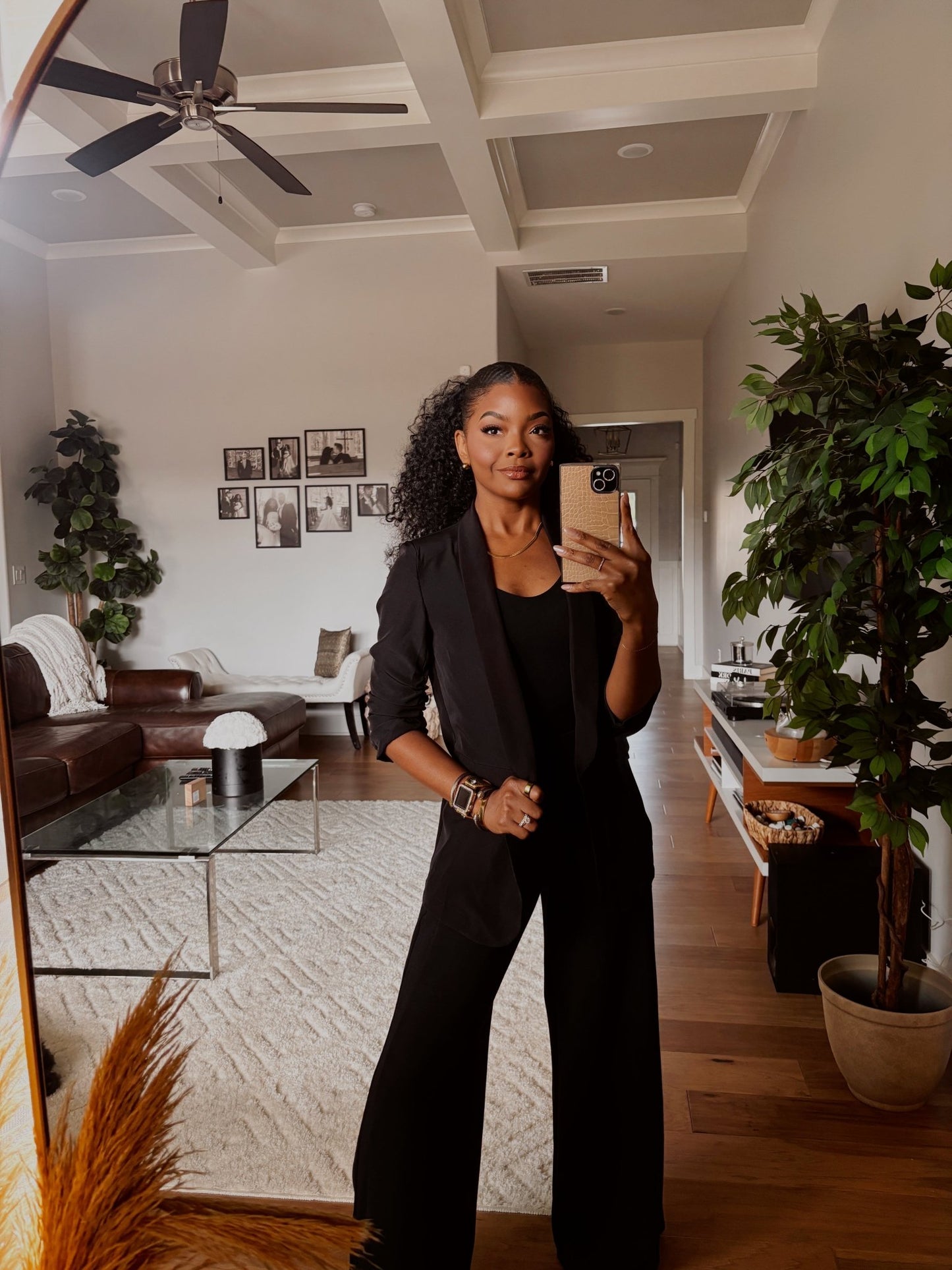 Woman wearing the Black Ruched Sleeve Blazer snaps a mirror selfie in a chic, office-ready room with plants and framed photos.