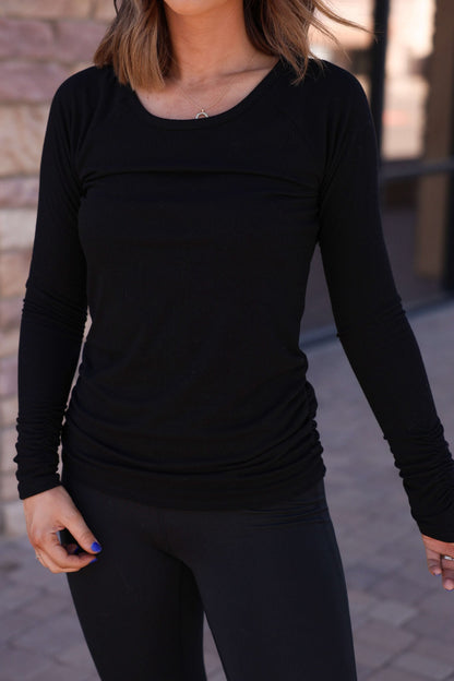 Woman in a Black Ruched Sleeve Ribbed Top - DOORBUSTER and black leggings, highlighting modern women's fashion on a walkway.