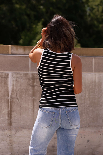 A woman in a Black Striped Rib Button Tank Top stands outdoors, facing away from the camera.