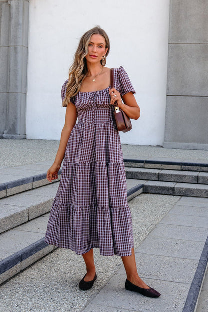 Woman in a BLU PEPPER B6FD1108 Mocha Midi Dress holding a brown purse, standing on outdoor steps by a modern stone building.