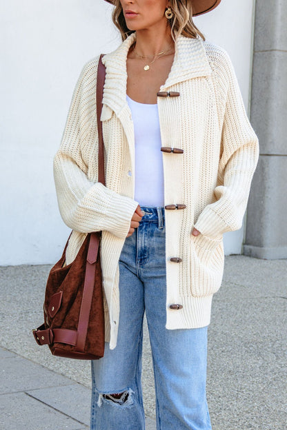 Woman wearing BLU PEPPER J6FJ1011 IVORY SWEATER, white top, ripped jeans, brown hat, and carrying a brown shoulder bag.