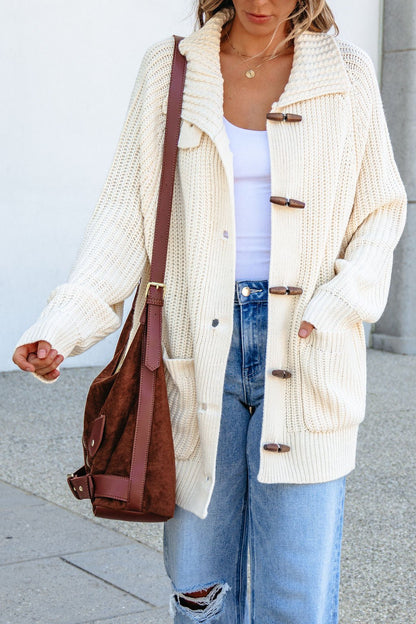 A woman wears a BLU PEPPER J6FJ1011 Ivory Sweater, white top, ripped jeans, and carries a brown suede bag over her shoulder.
