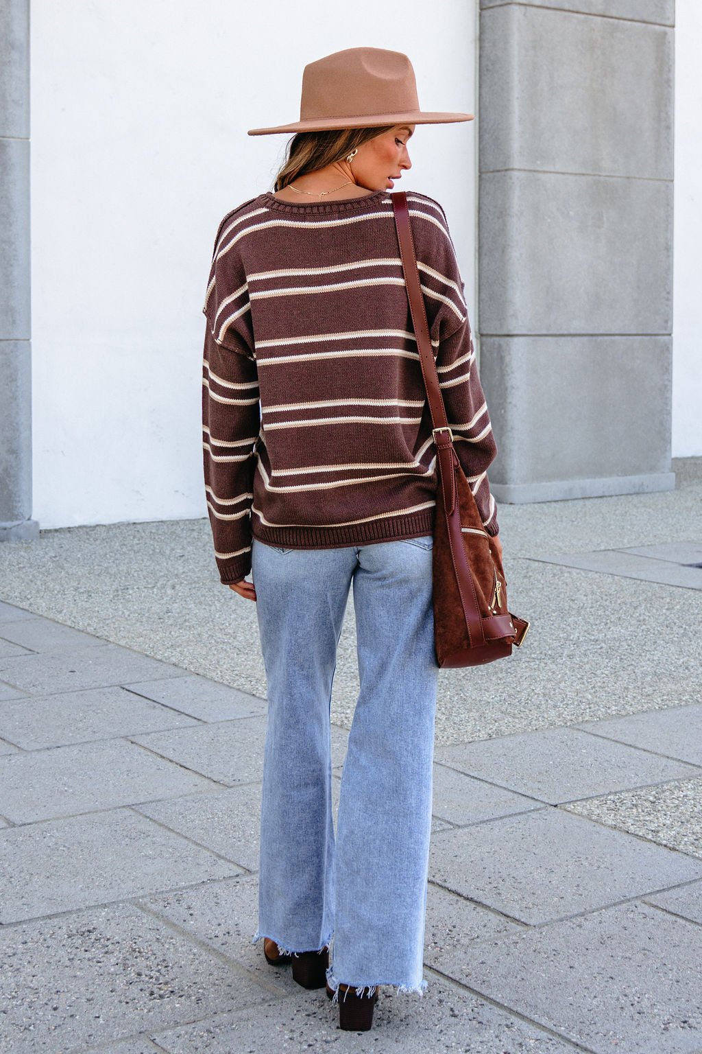 Individual wearing a tan hat and BLU PEPPER J6FT1014 BROWN STRIPED SWEATER stands with back to camera on city sidewalk.