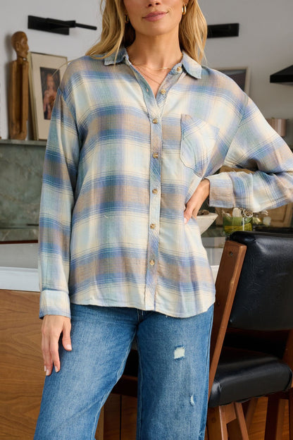 A woman wears a Blue Plaid Button Down Flannel Shirt and ripped jeans, standing confidently in a modern kitchen.
