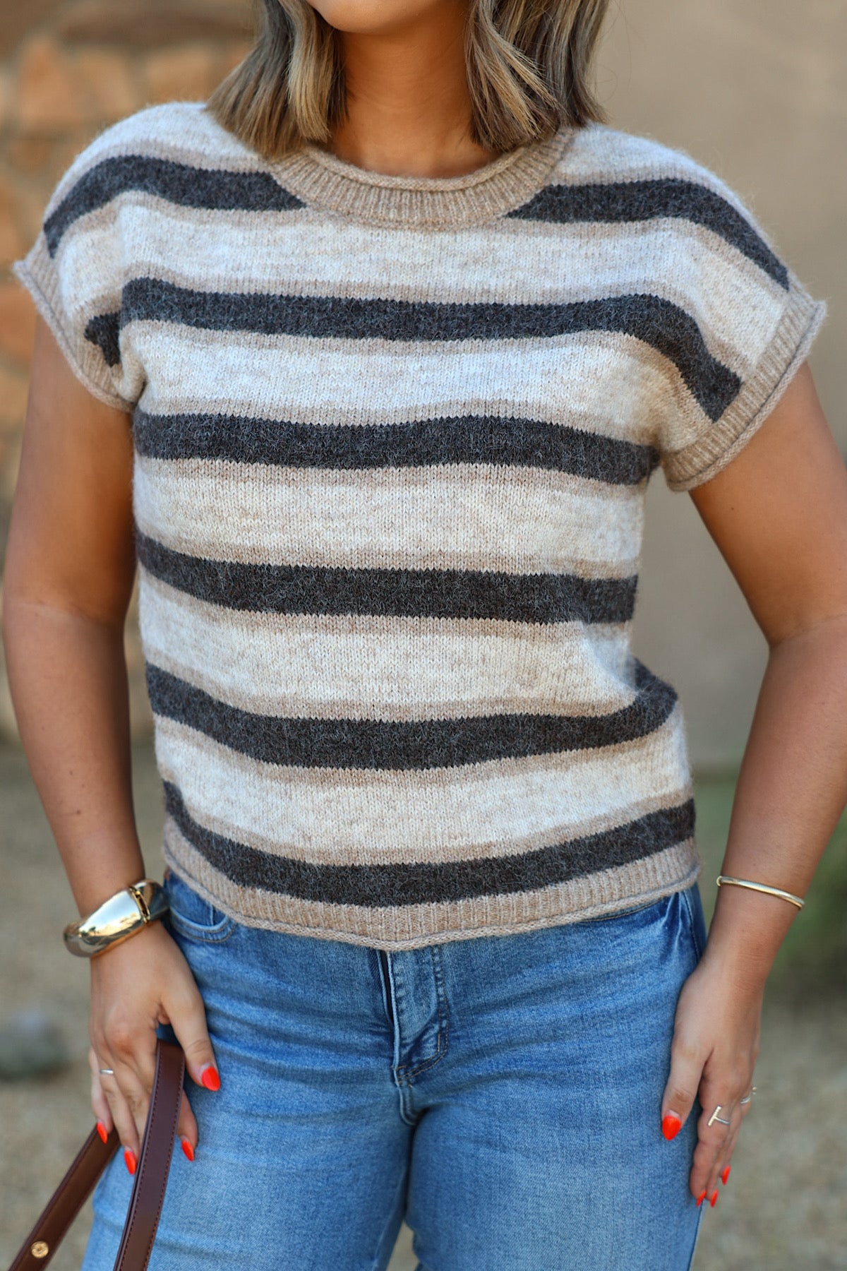 A woman wears a BLUPEPPER B6FT1055 dark brown striped sleeveless sweater with blue jeans, holding a brown bag.