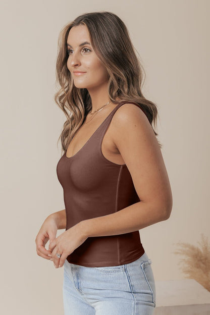 Woman with wavy brown hair in a Brown Double Lined Scoop Neck Jersey Tank and light blue jeans, standing sideways and smiling.
