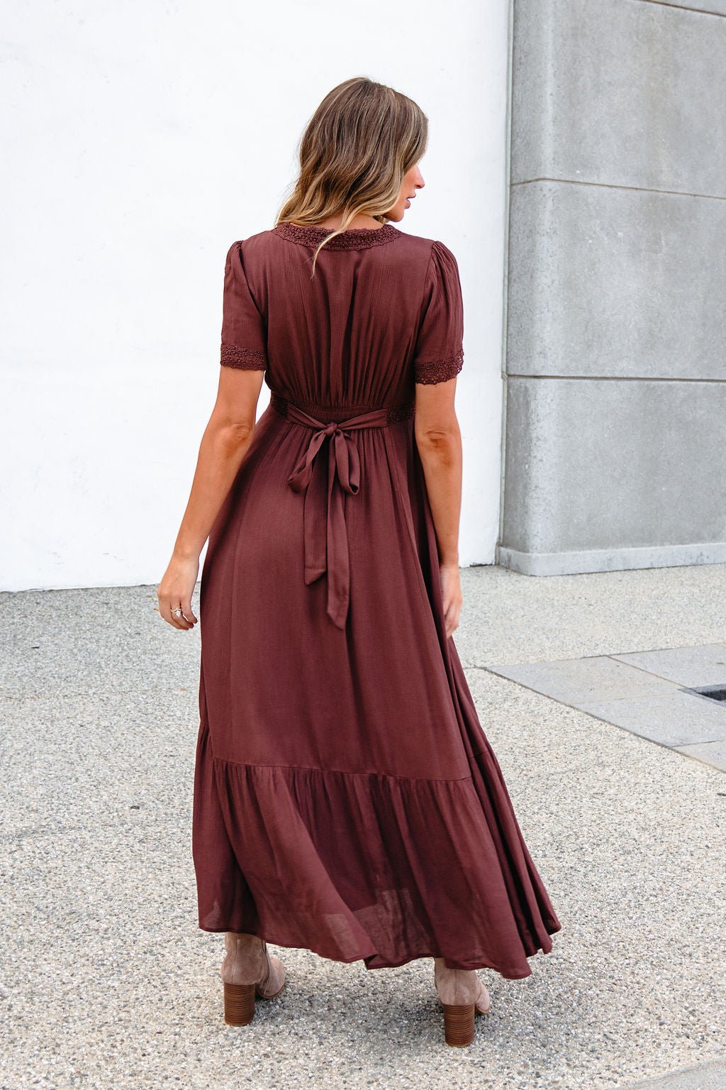 Woman outdoors in a Brown Lace Trim Maxi Dress, short sleeves and button front visible as she faces away.