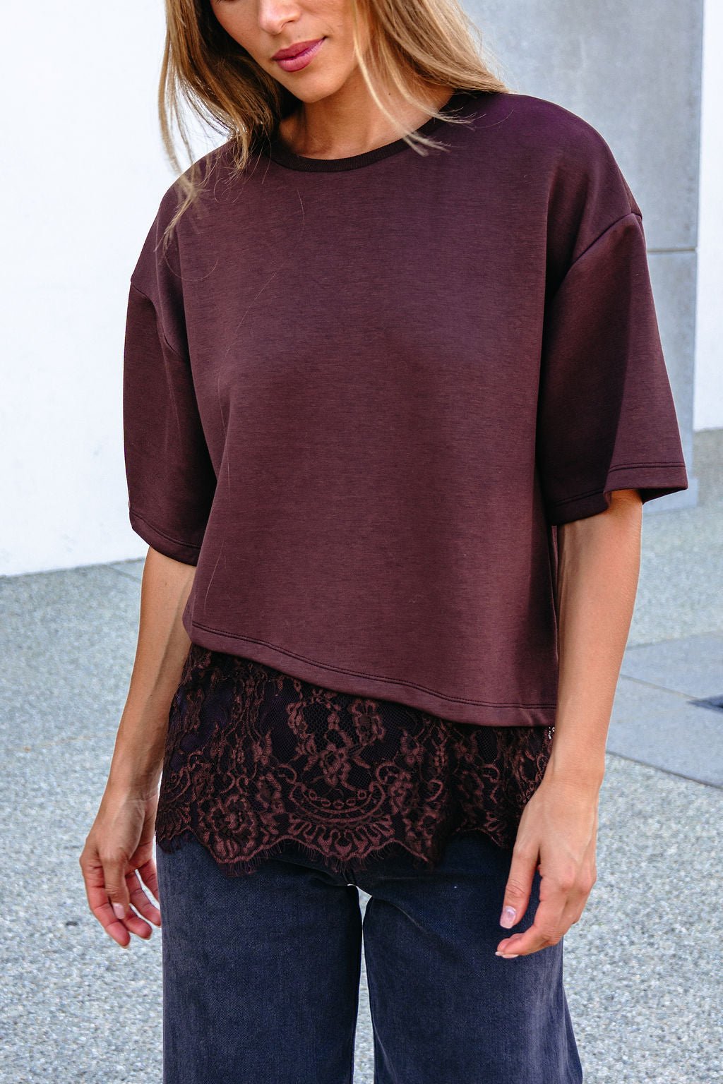 Woman in a Brown Lace Trim Short Sleeve Top, layered over a shirt with dark pants, standing outdoors.