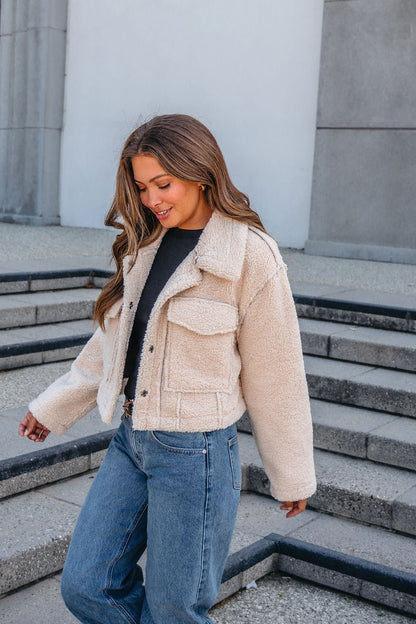 A woman in a Brown Mix Reversible Suede Sherpa Jacket and blue jeans walks down steps, smiling—perfect for fall.