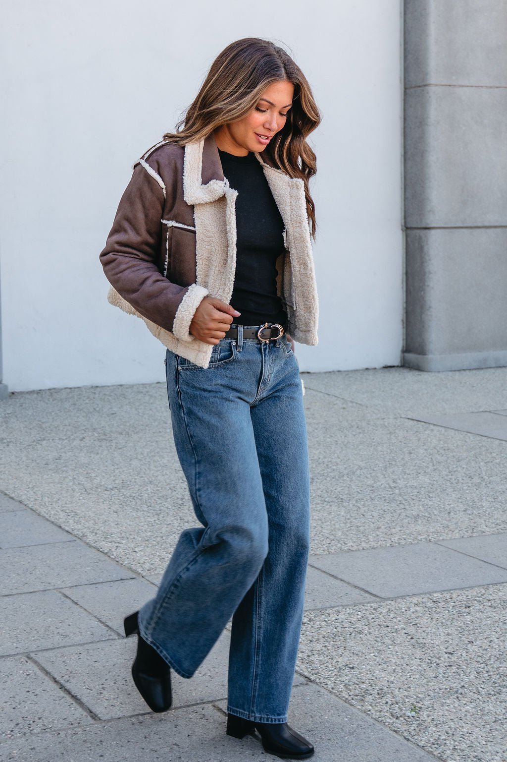 Woman walking outside in the Brown Mix Reversible Suede Sherpa Jacket—an essential that elevates fall jeans and boot looks.