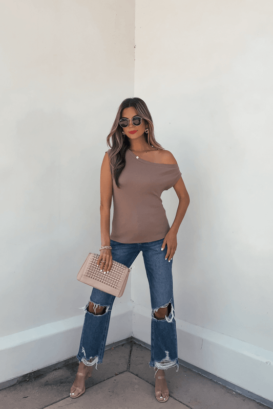 Woman in sunglasses and red lipstick wears a Brown Off The Shoulder Ribbed Top, ripped jeans, clear heels, and a blush pink clutch.