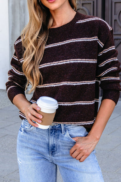 Woman in a Brown Rib Knit Striped Sweater and jeans, holding coffee outdoors with loose wavy hair.