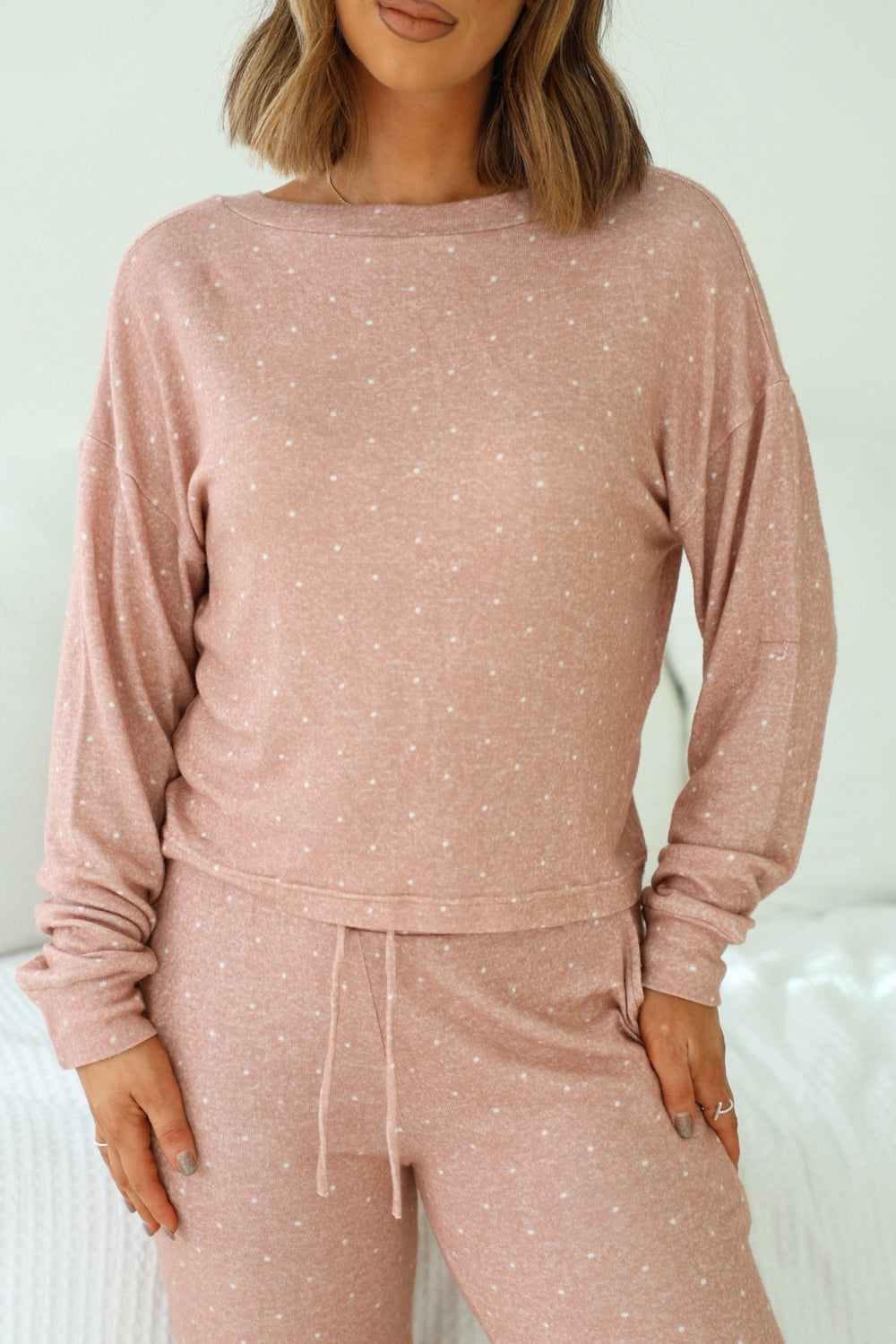 Woman wearing the Buttery Soft Blush Polka Dot Lounge Top, crafted from brushed hacci fabric, standing relaxed.