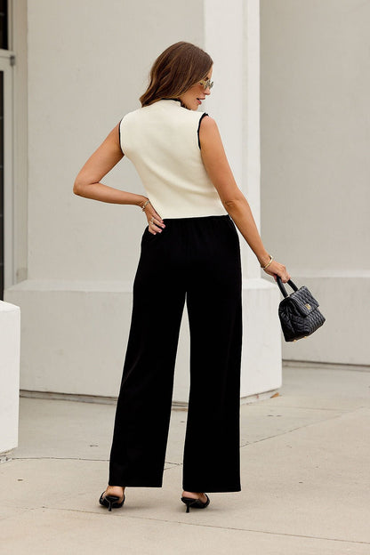 Woman in sleeveless cream top and Buttery Soft Dress Pants - Black stands outdoors holding a small black purse, facing away.