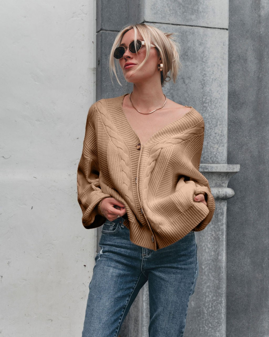 Woman in sunglasses and blue jeans wears the Camden Button Down Cardigan - Taupe, featuring balloon sleeves.