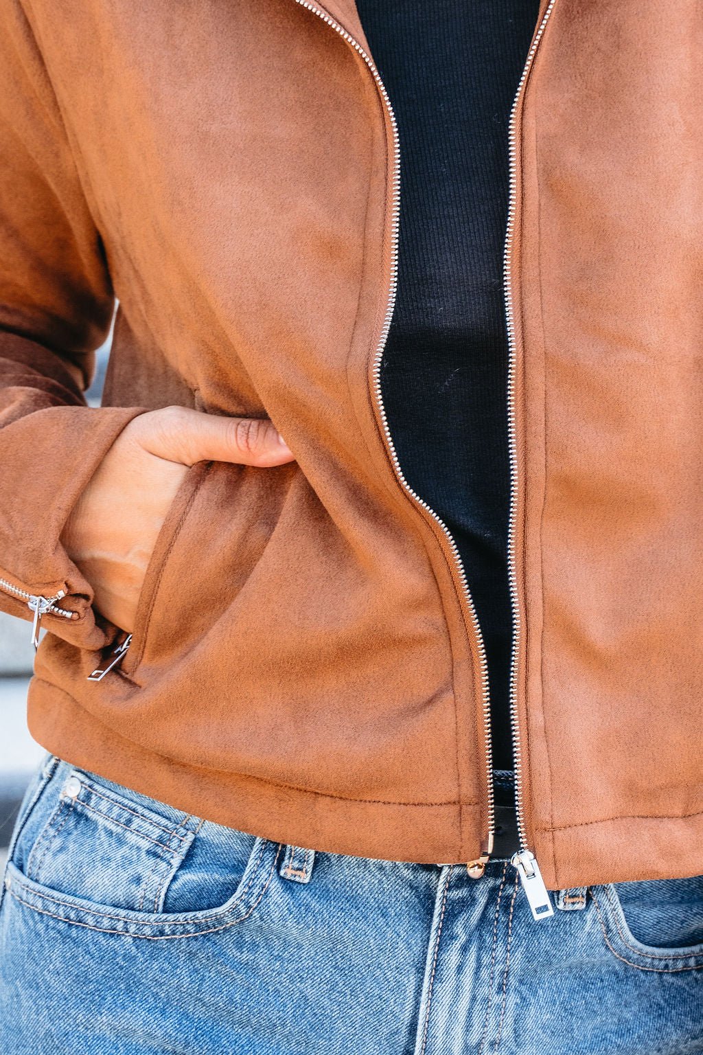 Model wears a Camel Suede Zip Up Jacket over a black shirt and blue jeans, with one hand in the jacket pocket.